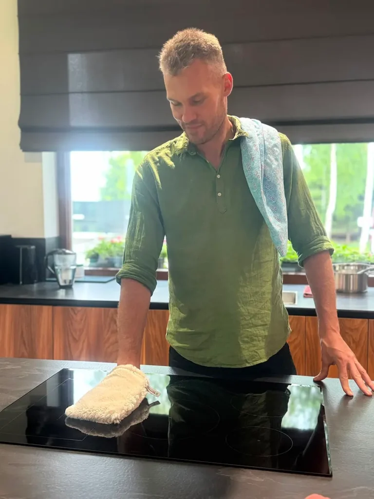 Przedstawiciel Raypath Adrian Buczyński sprząta w nowoczesnej kuchni rękawicą Raypath, kuchenkę indukcyjną